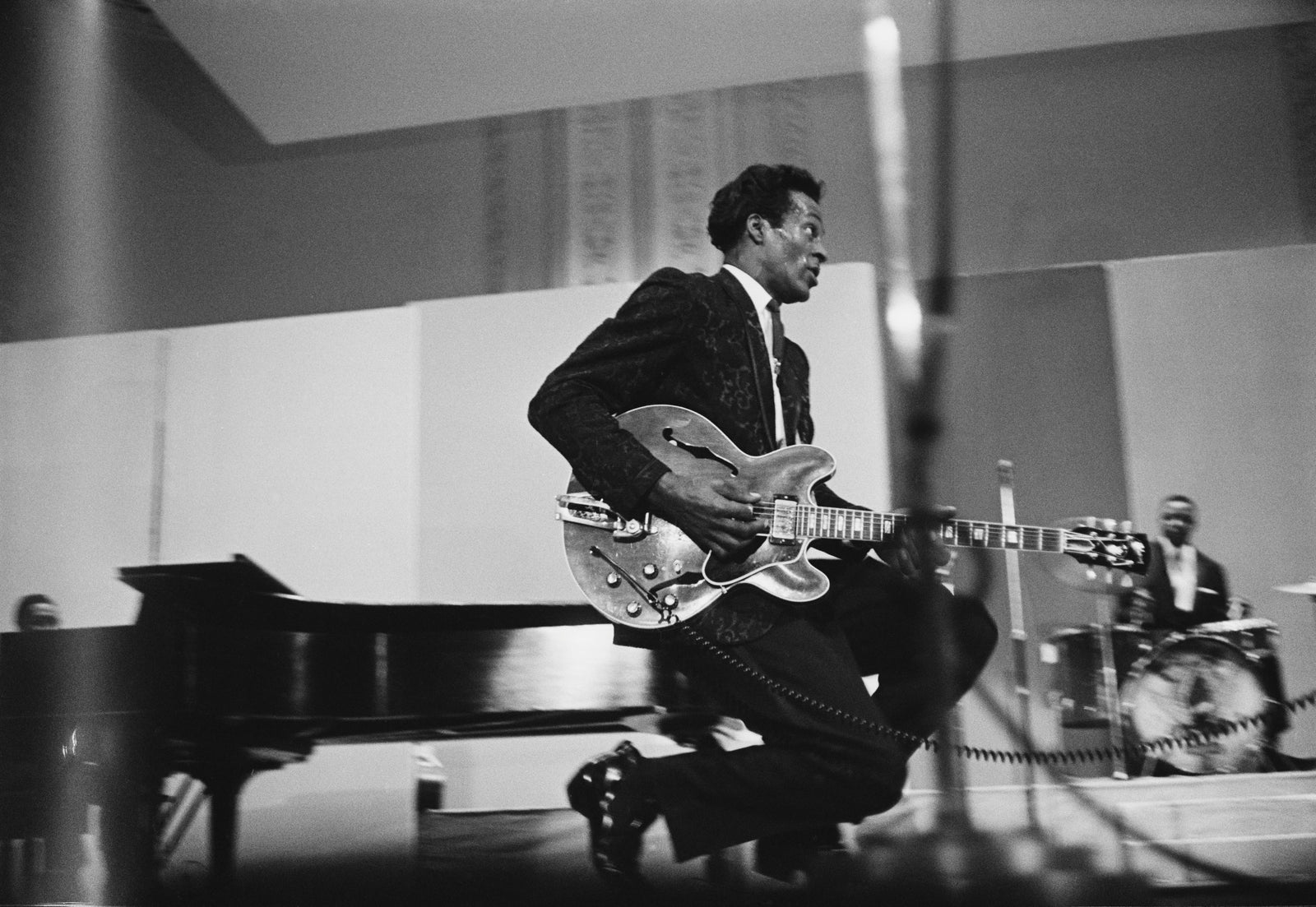 Black and white photograph of Chuck Berry performing his trademark duckwalk with guitar on stage, circa 1970