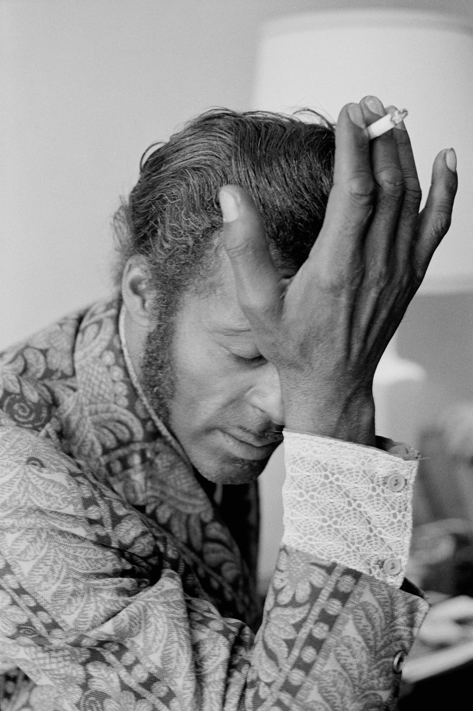 Black and white close-up of Chuck Berry in a paisley shirt, hand pressed to his forehead with a cigarette between his fingers, 1972