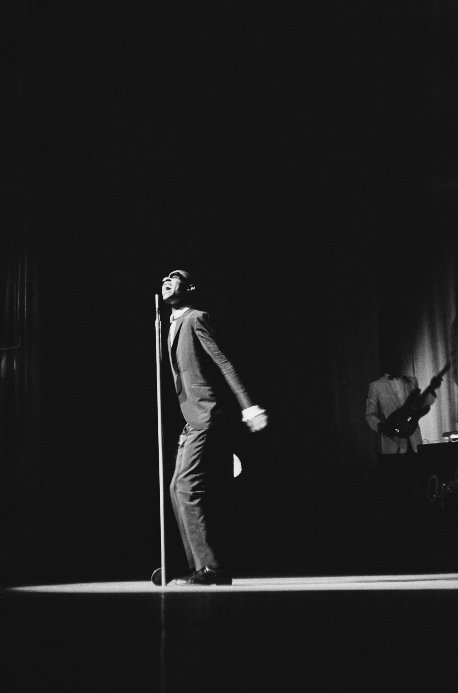 Black and white photograph of a young Stevie Wonder performing alone on a spotlit stage at the Apollo Theater, New York, circa 1963