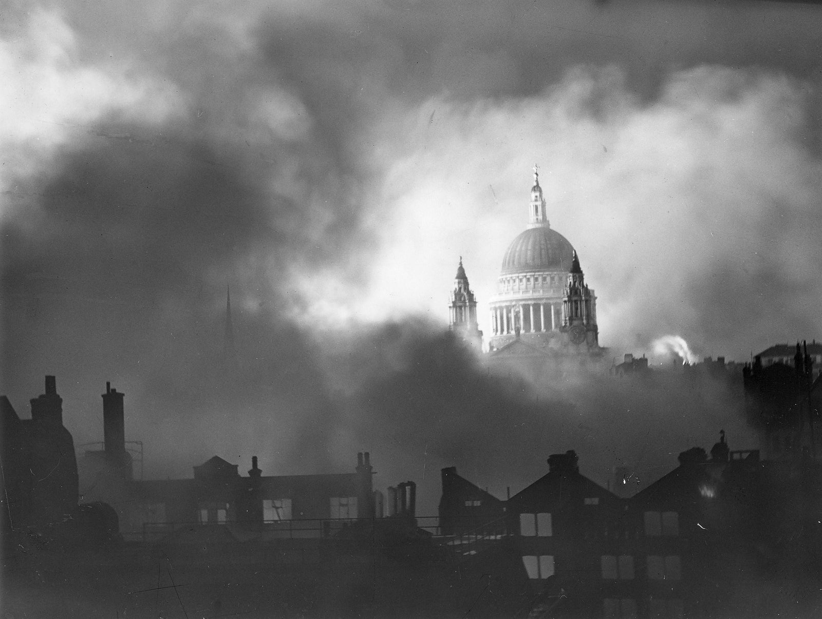Black and white photograph of the dome of St Paul's Cathedral rising above smoke and burning buildings during the London Blitz