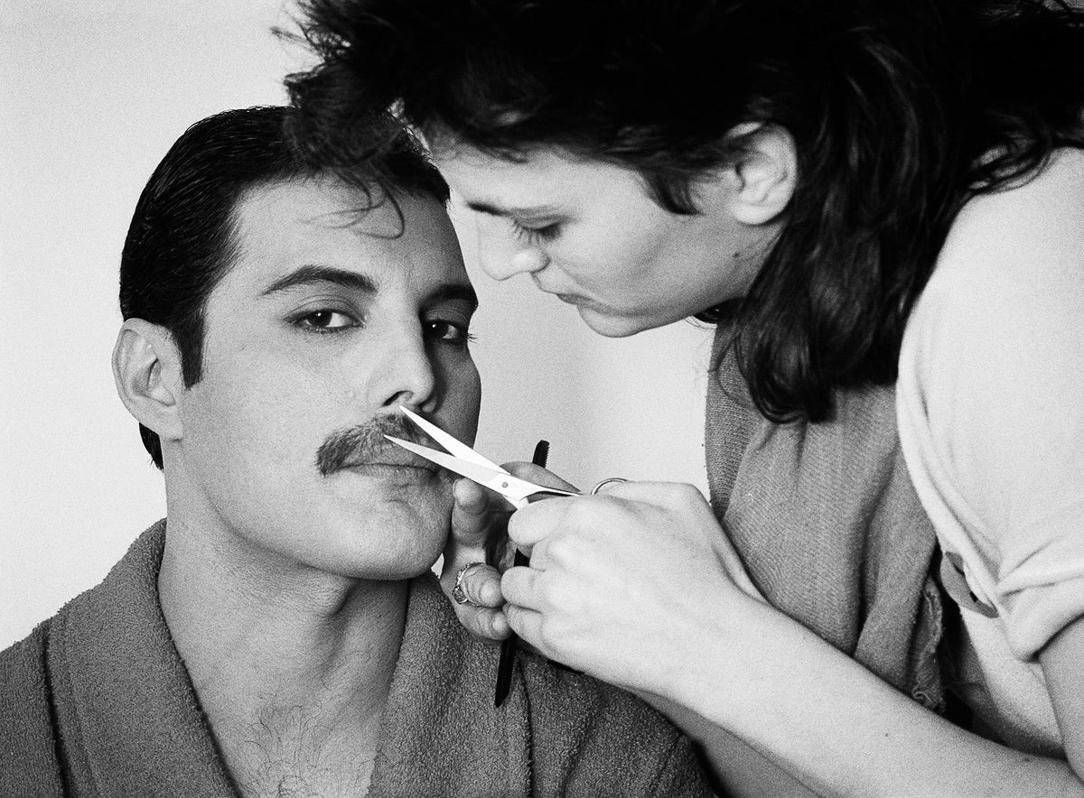 Black and white photograph of Freddie Mercury having his moustache trimmed with scissors, 1982
