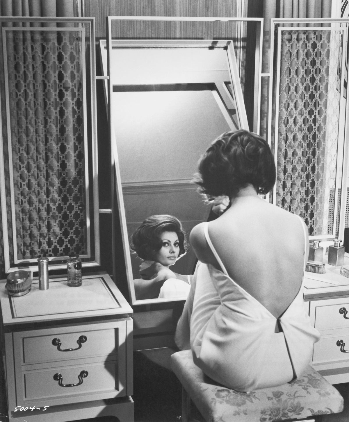 Black and white photograph of Sophia Loren in a backless dress seated at a dressing table mirror in A Countess from Hong Kong, 1967