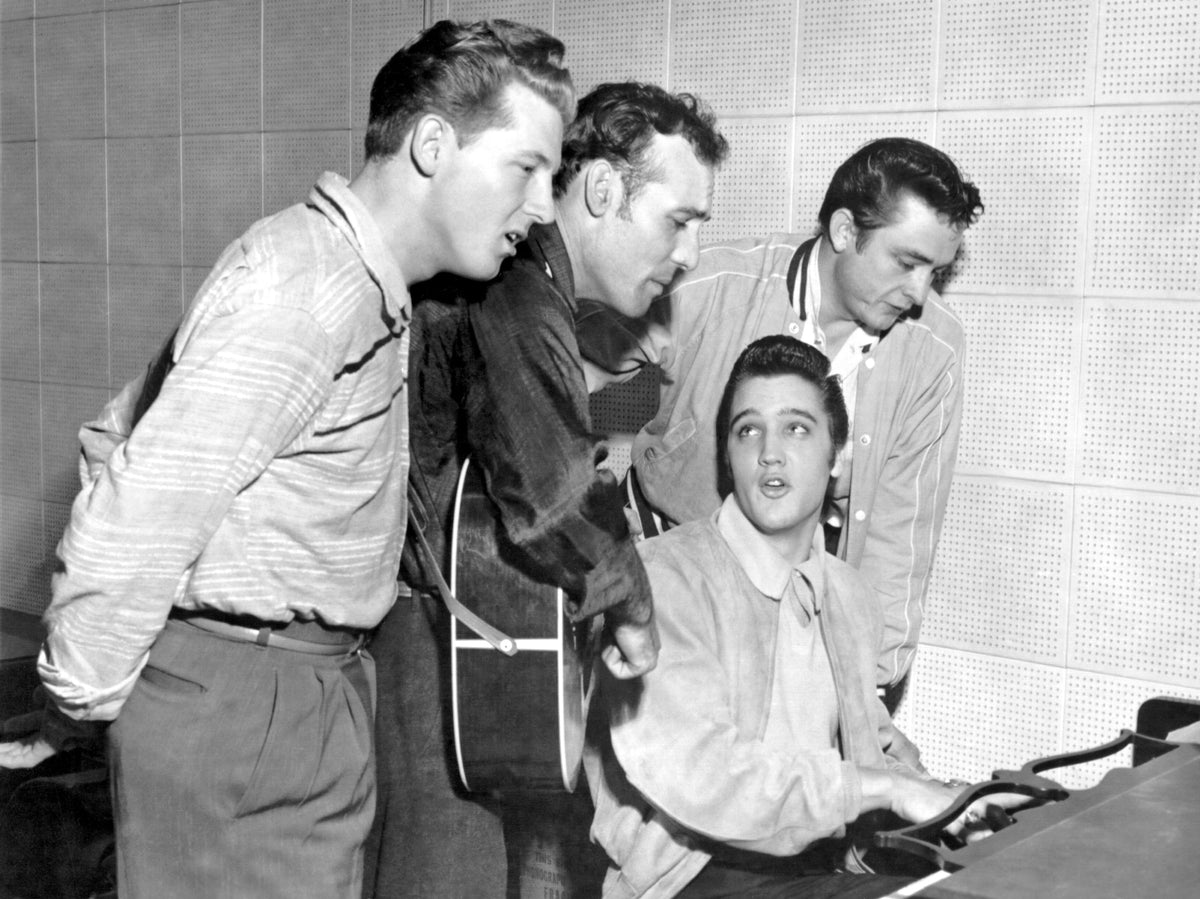 Black and white photograph of the Million Dollar Quartet, Jerry Lee Lewis, Carl Perkins, Elvis Presley and Johnny Cash, gathered round a piano at Sun Studios, 1956