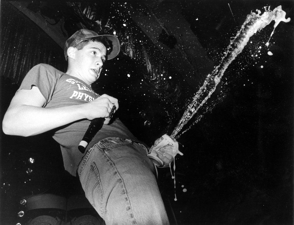 Black and white photograph of Ad-Rock of the Beastie Boys spraying a can of beer on stage at the Hollywood Palladium, 1987