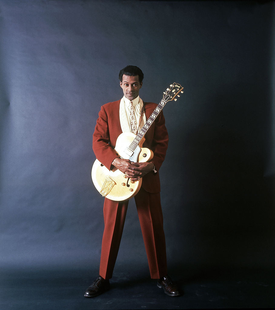 Colour studio portrait of Chuck Berry in a red suit holding a white Gibson guitar, Chicago, circa 1958
