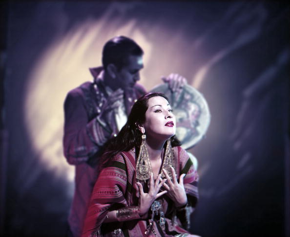 Colour photograph of Yma Sumac in Peruvian dress with her husband Moises Vivanco behind her, from the Inca Taqui album shoot, 1953