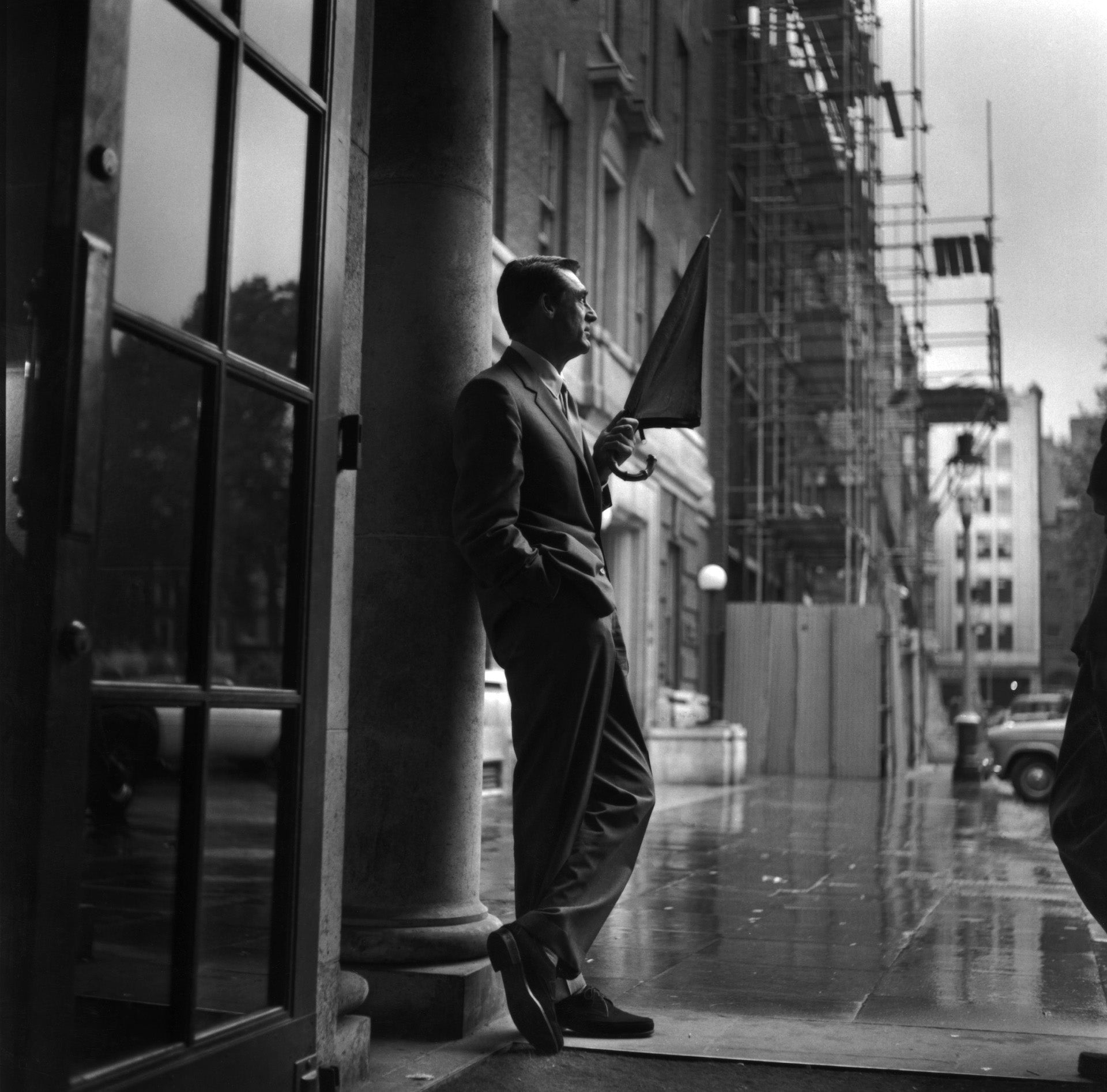 Cary In Rain by Express/Getty Images. British-born American actor Cary Grant sheltering in a hotel porch as he waits for the rain to stop.. Open Edition Resin Photographic Print. Square orientation. Available at Electric Gallery, London, UK.