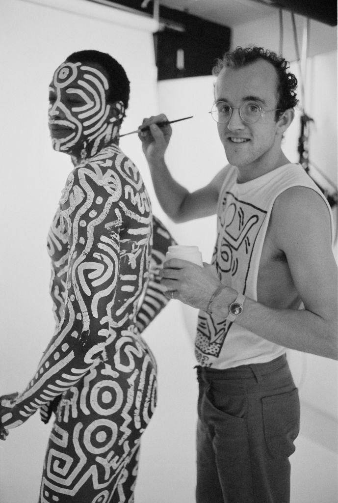 Black and white photograph of Keith Haring painting his white line patterns onto the body of dancer Bill T. Jones, London, 1983