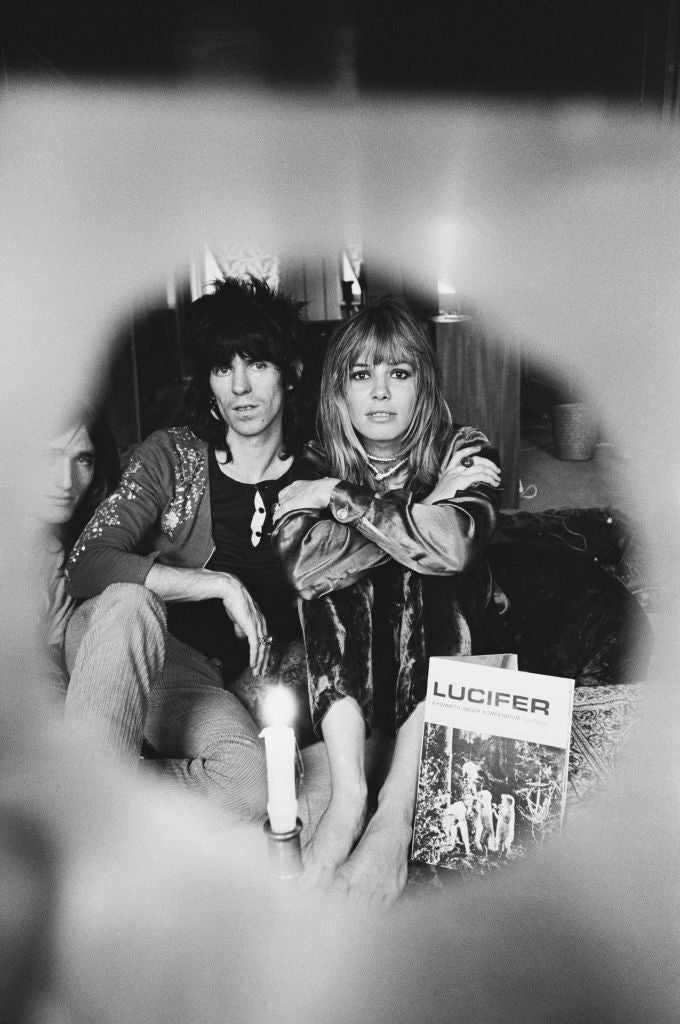 Black and white photograph of Keith Richards and Anita Pallenberg sitting together, framed through a soft circular vignette, UK, 1969
