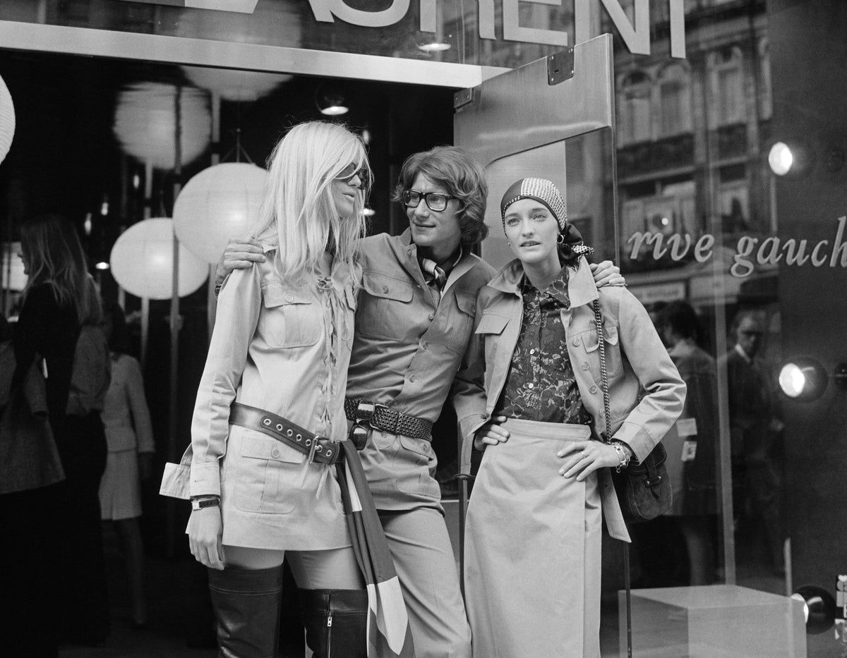 Black and white photograph of Yves Saint Laurent with models Betty Catroux and Loulou de la Falaise outside his Rive Gauche shop