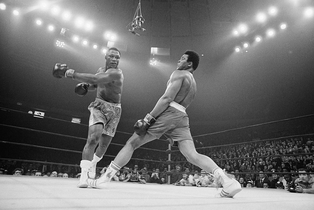 Black and white photograph of Muhammad Ali leaning away from a punch thrown by Joe Frazier in the ring at Madison Square Garden, 1971
