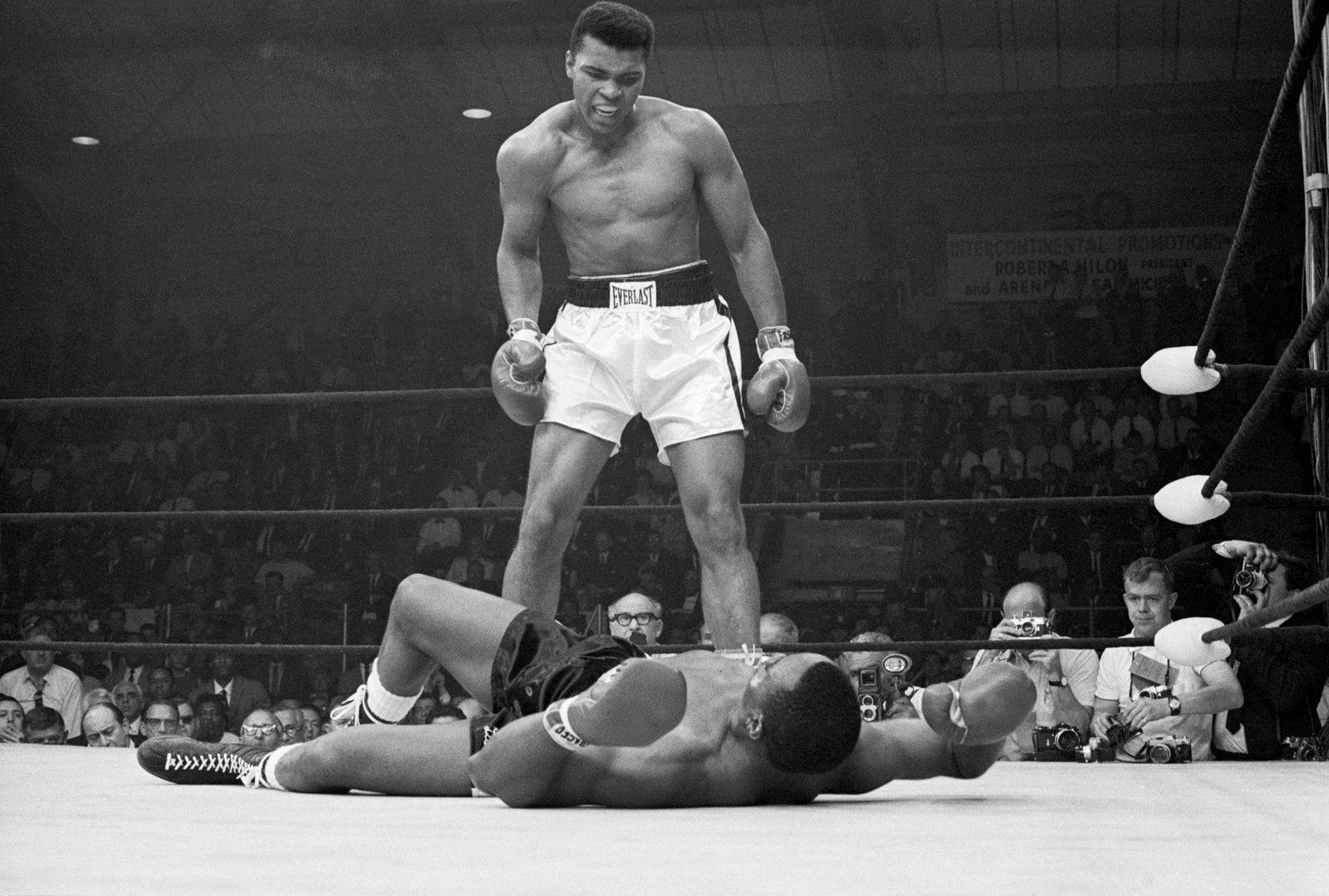 Black and white photograph of Muhammad Ali standing over a floored Sonny Liston in the boxing ring at Lewiston, Maine, 1965