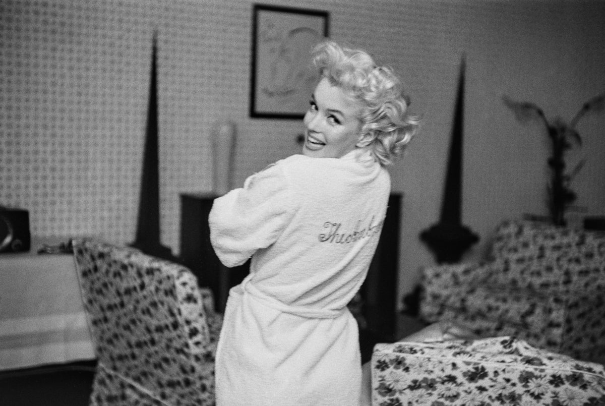 Black and white photograph of Marilyn Monroe glancing over her shoulder in a white Ambassador Hotel robe, New York, 1955