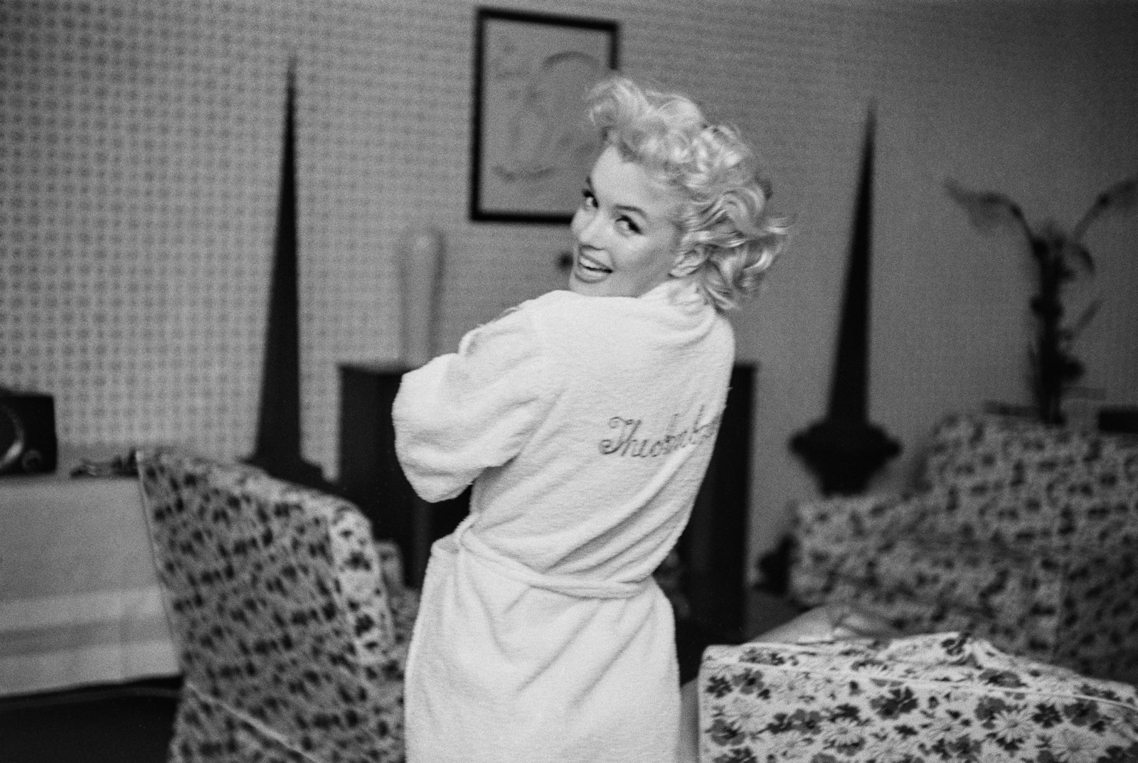 Black and white photograph of Marilyn Monroe glancing over her shoulder in a white Ambassador Hotel robe, New York, 1955