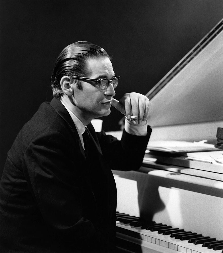Black and white photograph of Bill Evans in glasses seated at a grand piano, chin resting on his hand, BBC Jazz 625, London, 1965