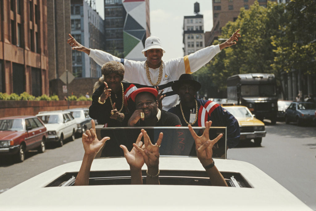 Colour photograph of LL Cool J and his crew riding through New York City in the sunroof of a white limousine, 1987
