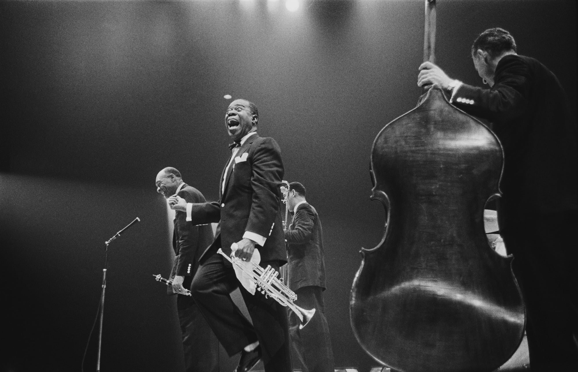 Louis Armstrong On Stage by Hulton Archive/Getty Images, 1956. American jazz trumpeter and bandleader Louis 'Satchmo' Armstrong, shouts after clarinettist Edmund Hall's solo, on stage during the band's British tour, May 19. Open Edition Resin Photographic Print. Landscape orientation. Available at Electric Gallery, London, UK.