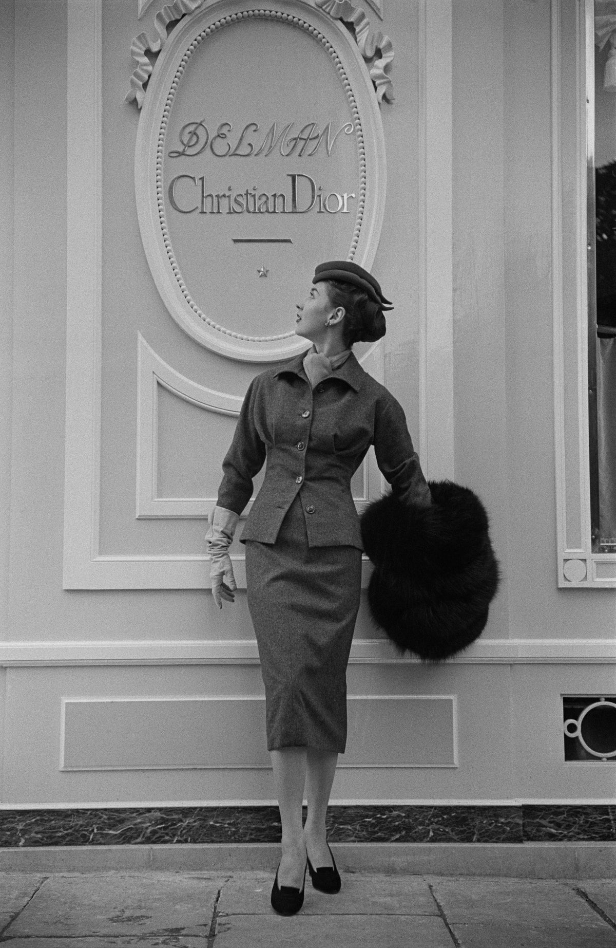 Dior boutique in Paris by Kurt Hutton/Getty Images, 1953. A model wearing a muff and suit outside Christian Dior's boutique in Paris.. Open Edition Resin Photographic Print. Portrait orientation. Available at Electric Gallery, London, UK.
