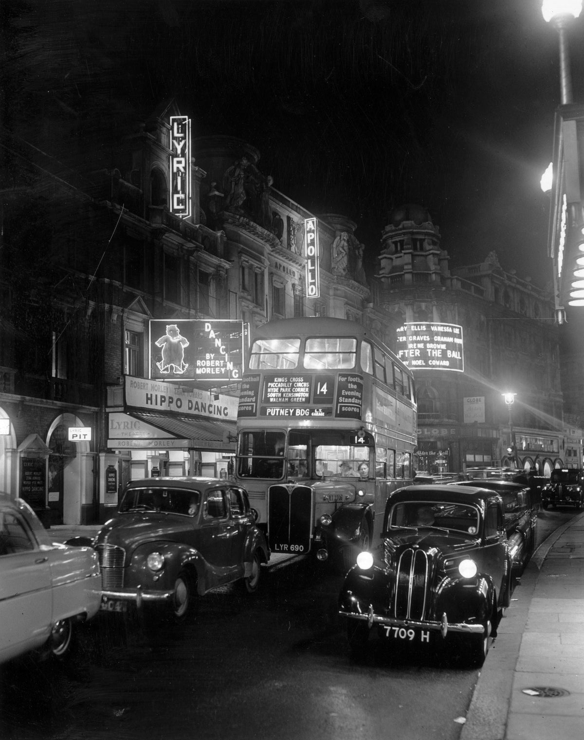 Street Night by Monty Fresco/Getty Images, 1954. A bus and cars travelling down Shaftesbury Avenue, London, in front of an illuminated Lyric Theatre, at night.. Open Edition Resin Photographic Print. Portrait orientation. Available at Electric Gallery, London, UK.