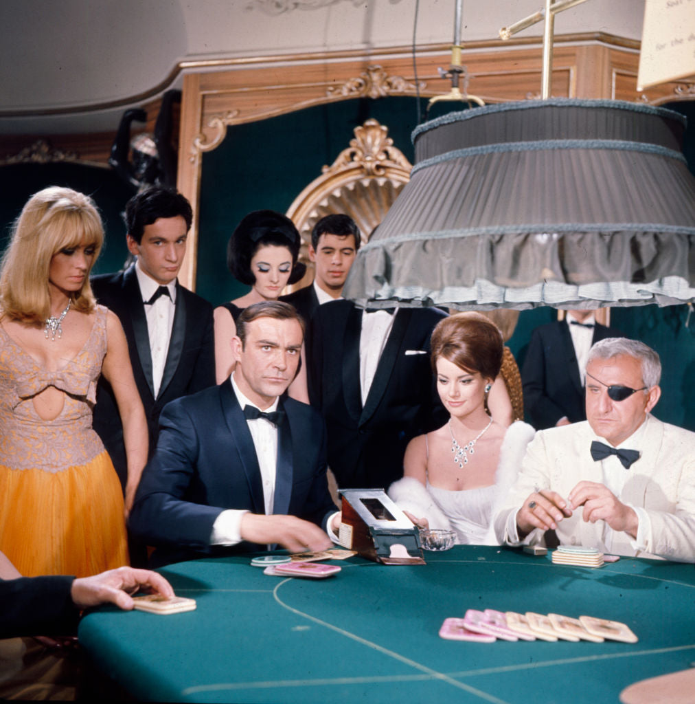 Sean Connery In Thunderball by Popperfoto/Getty Images, 1965. Scottish actor Sean Connery performs in character as James Bond with Italian actor Adolfo Celi as eye patch-wearing Emilio Largo in a casino scene from the film 'Thunderball' in. Open Edition C-Type Photographic Print. Square orientation. Available at Electric Gallery, London, UK.