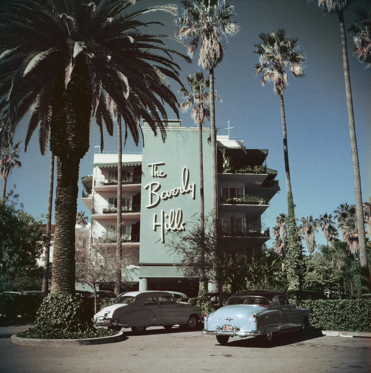 Beverly Hills Hotel by Slim Aarons/Getty Images, 1957. Cars parked outside the Beverly Hills Hotel on Sunset Boulevard in California. Open Edition C-Type Photographic Print. Square orientation. Available at Electric Gallery, London, UK.