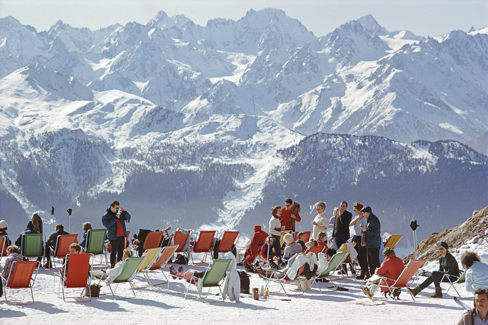 Lounging In Verbier by Slim Aarons/Getty Images, 1964. Holidaymakers in sun loungers on the slopes at Verbier, Switzerland. Open Edition C-Type Photographic Print. Landscape orientation. Available at Electric Gallery, London, UK.