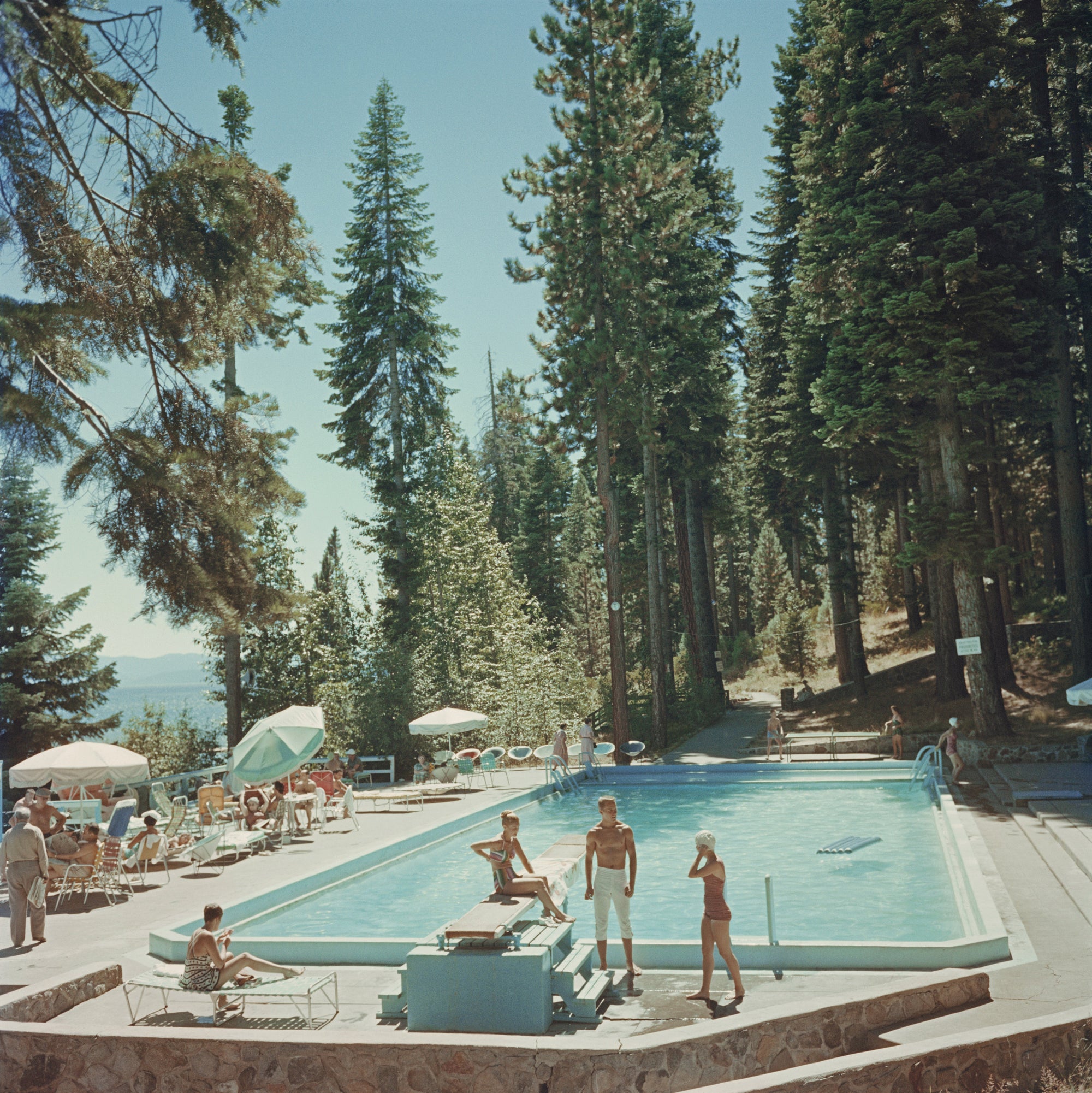 Pool At Lake Tahoe by Slim Aarons/Getty Images, 1959. Bathers by a pool at the Tahoe Tavern on the shore of Lake Tahoe, California. Open Edition C-Type Photographic Print. Square orientation. Available at Electric Gallery, London, UK.