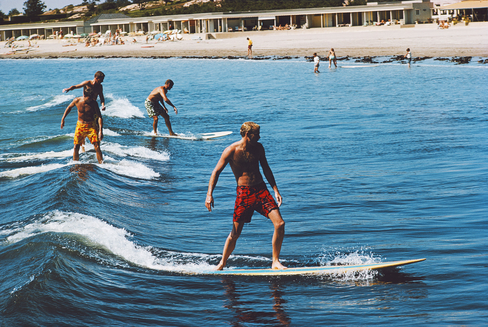 Surfing Brothers by Slim Aarons/Getty Images, 1965. Freddie and Howard Cushing surfing with friends at Bailey's Beach in Newport.. Open Edition C-Type Photographic Print.. Landscape orientation. Available at Electric Gallery, London, UK.