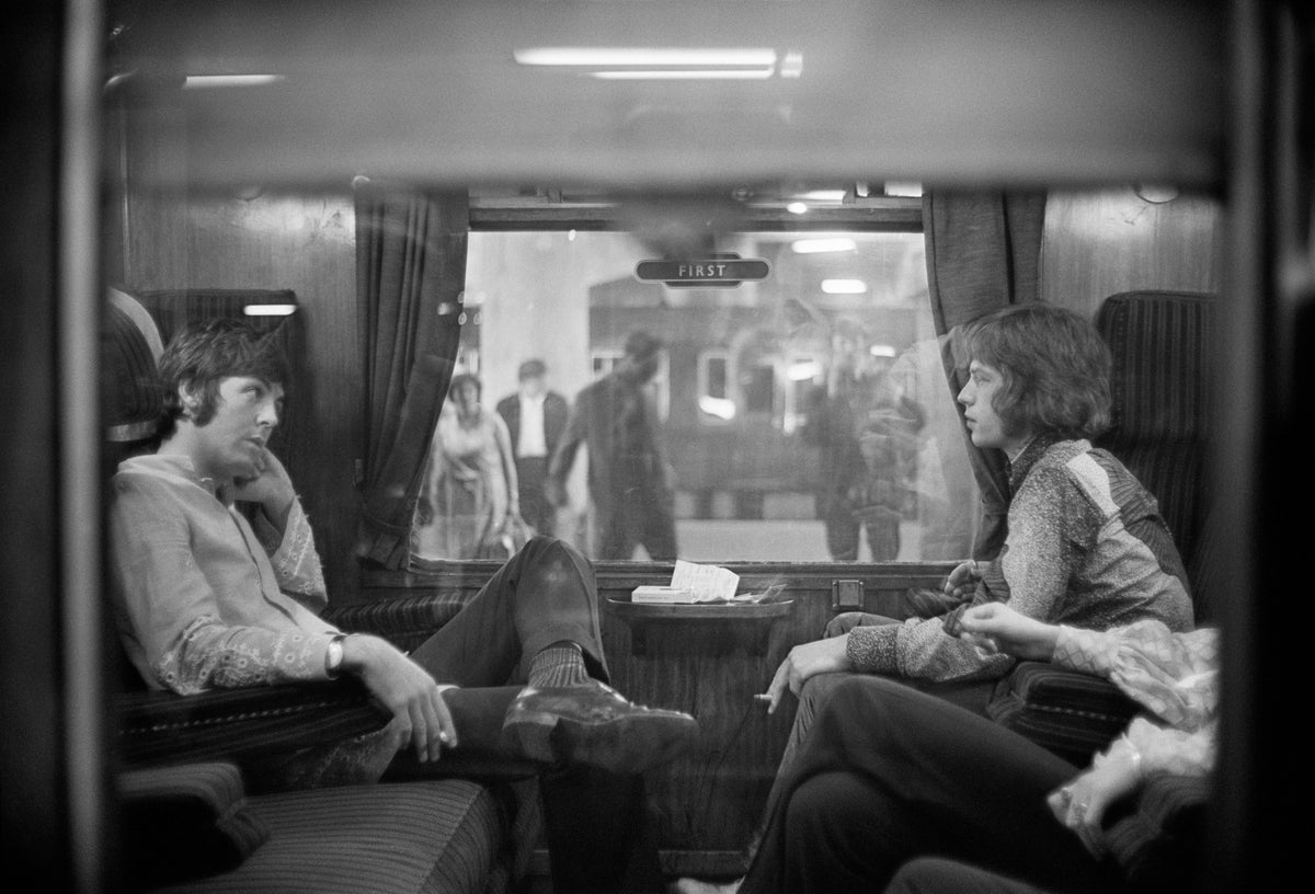 First Class Travel by Victor Blackman/Getty Images, 1967. Paul McCartney of the Beatles and Mick Jagger of the Rolling Stones sit opposite each other on a train at Euston Station, waiting for departure to Bangor.. Open Edition Resin Photographic Print. Landscape orientation. Available at Electric Gallery, London, UK.