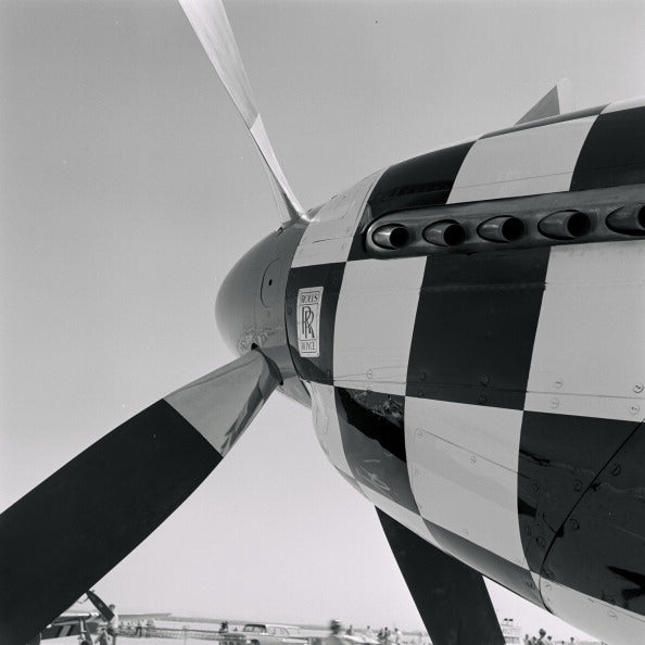 Black and white close-up of the checkerboard nose and propeller of a P-51 Mustang at a California air show, 1965