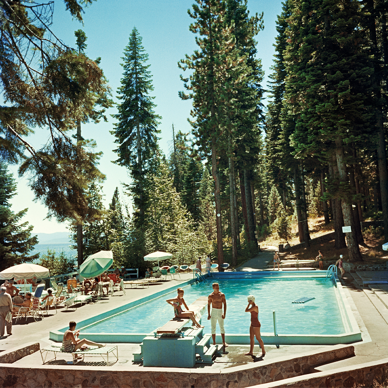 Pool At Lake Tahoe by Slim Aarons/Getty Images, 1959. Bathers by a pool at the Tahoe Tavern on the shore of Lake Tahoe, California. Open Edition C-Type Photographic Print. Square orientation. Available at Electric Gallery, London, UK.