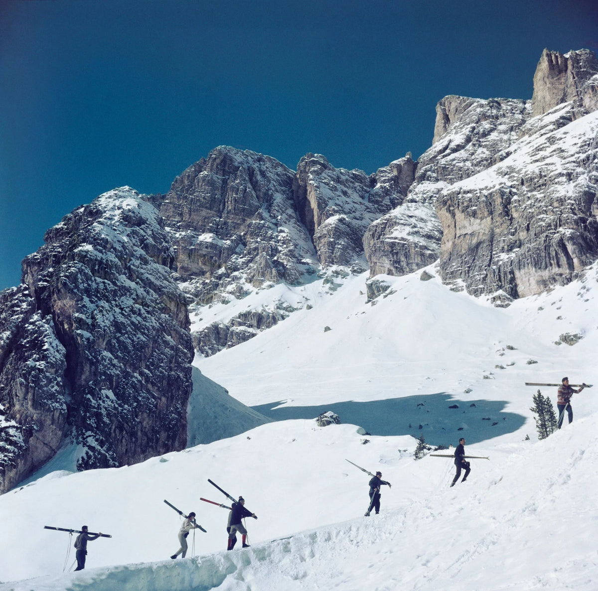 Skiers walk up a mountain in Cortina D'Ampezzo, a ski resort in northern Italy, 1962. Slim Aarons photograph.
