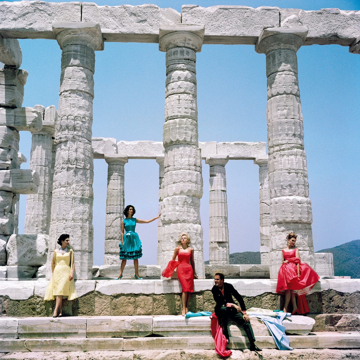 Greek fashion designer Dimitris Kritsas poses with four models against a backdrop of the ancient Doric temple to Poseidon at Sounion, July 1967. Slim Aarons photograph.