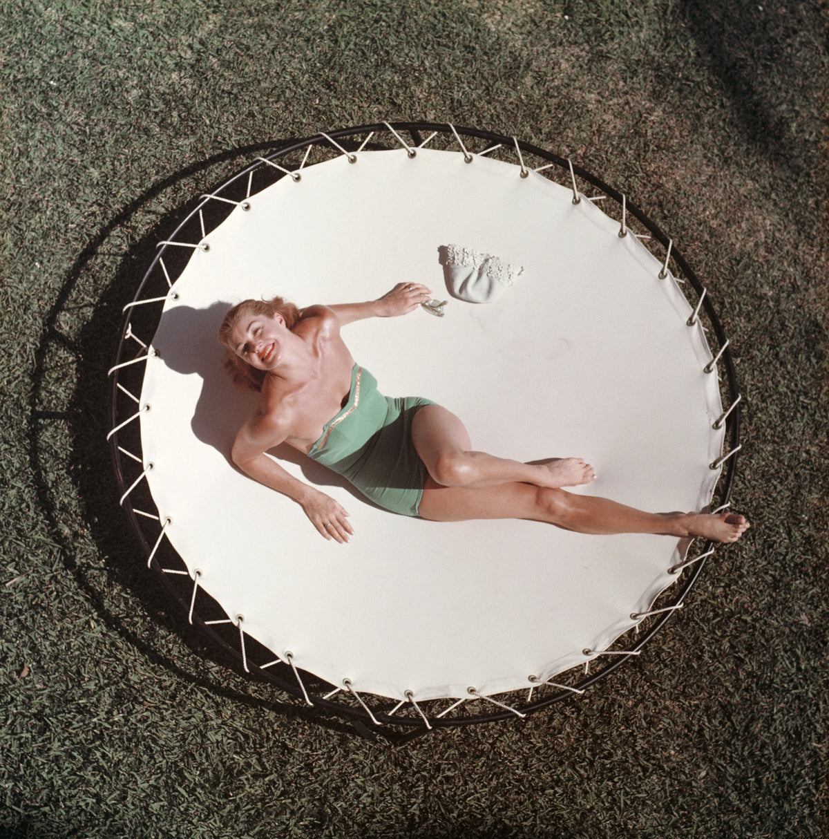 American swimmer and actress Esther Williams lounging on a trampoline, circa 1956. Slim Aarons photograph.