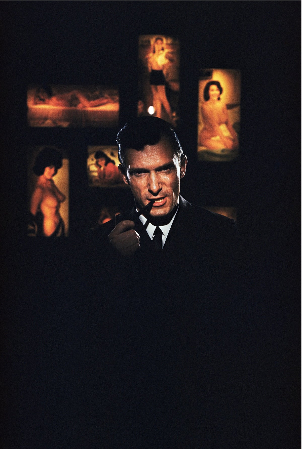 American publisher Hugh Hefner, founder of 'Playboy' magazine, surrounded by erotica at the Playboy Club in Chicago, 1961. Slim Aarons photograph.