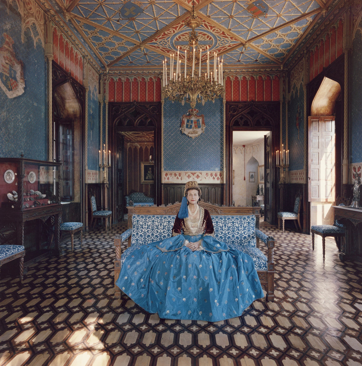 Madame Jean Serpieri sits in the ballroom of the Tour La Reine near Athens, wearing a gown which belonged to the wife of Otto, the first king of modern Greece, December 1961. The palace too originally belonged to King Otto, and was used as a summer home by the royal family. Slim Aarons photograph.