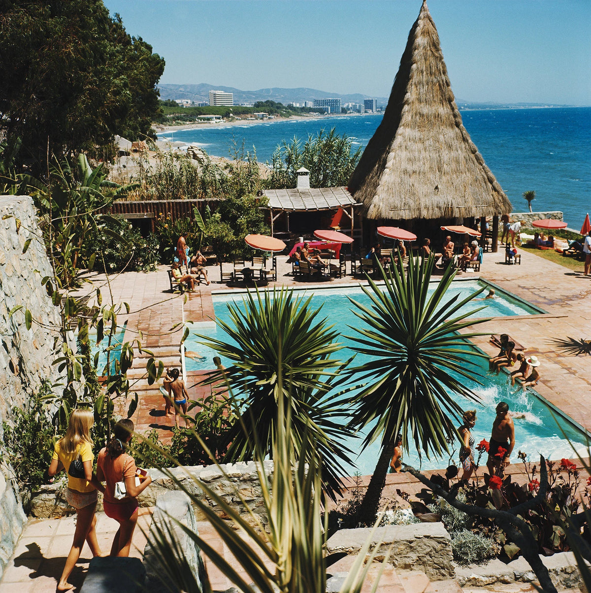 The swimming pool of the Marbella Club in Andalucia looks out over the sea, 1976. Slim Aarons photograph.