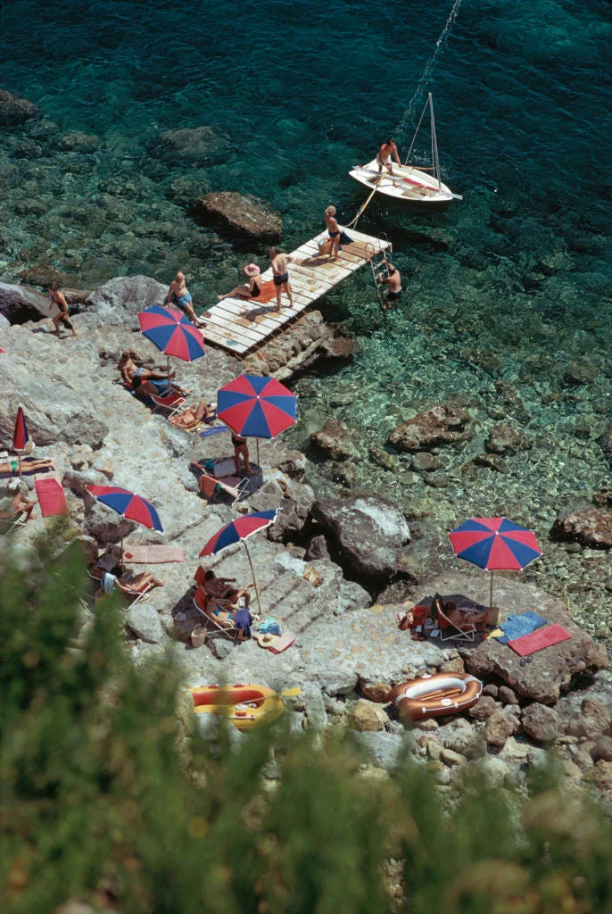 A jetty juts out from the rocky shoreline at the Hotel Il Pellicano in Porto Ercole, Tuscany, August 1973. Slim Aarons photograph.