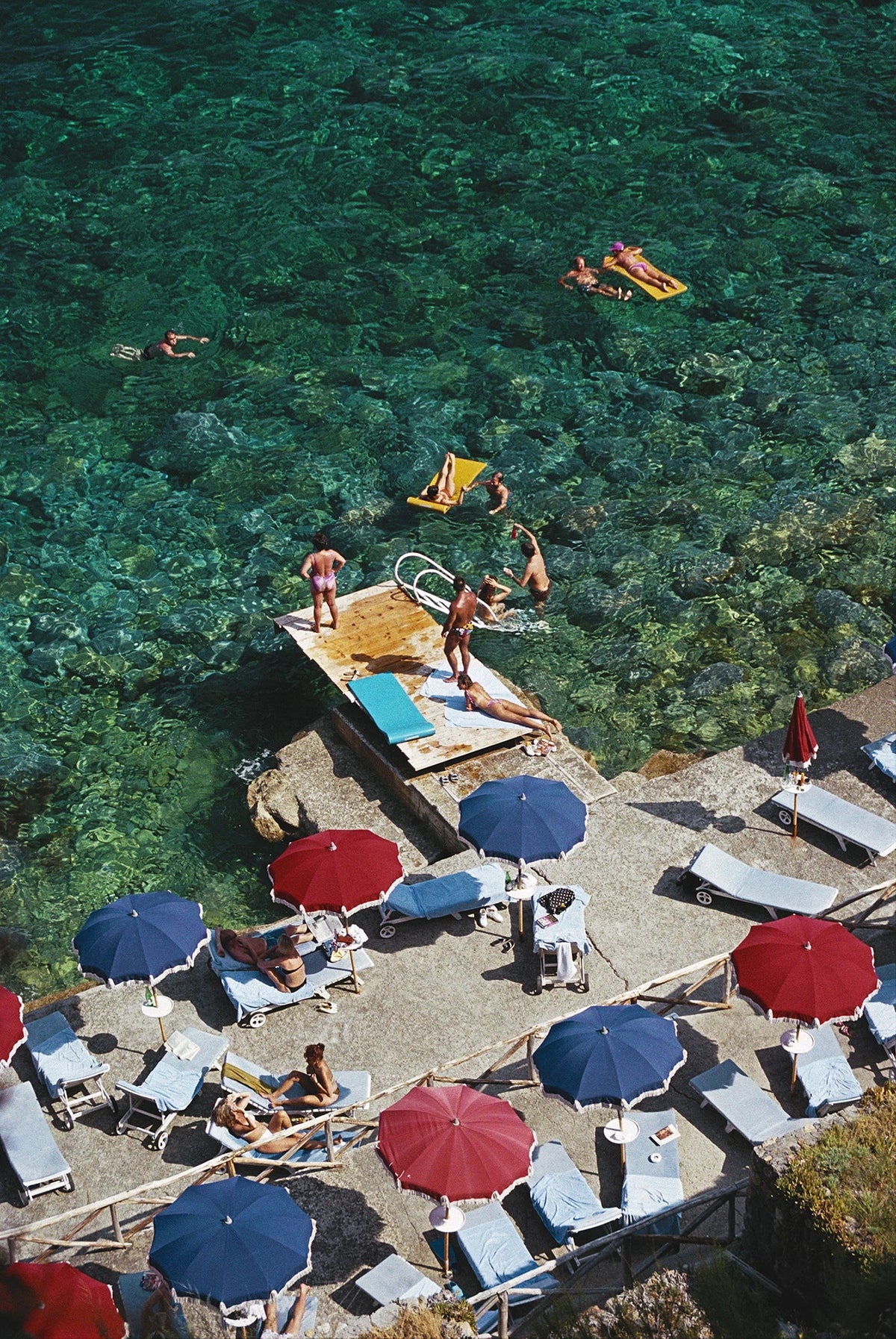 A jetty juts out from a rocky shoreline in Porto Ercole, Tuscany, July 1991. Slim Aarons photograph.