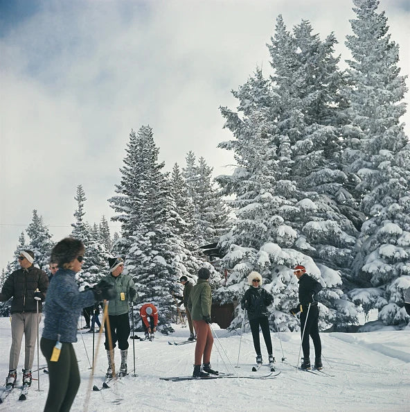 A group of skiers standing next to snow covered trees in Vail, Colorado, USA, 1964. Slim Aarons photograph.