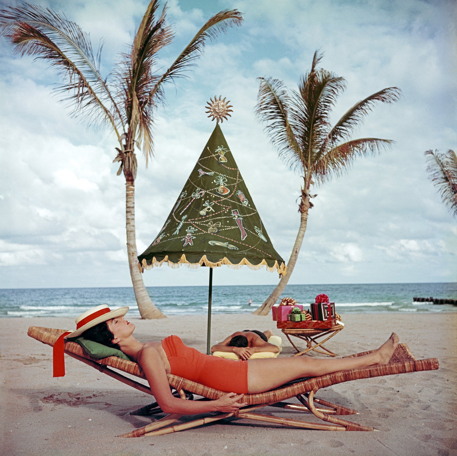 Palm Beach Idyll by Slim Aarons/Getty Images, 1955. A couple sunbathing by the sea at Palm Beach, Florida, circa. Open Edition C-Type Photographic Print. Square orientation. Available at Electric Gallery, London, UK.