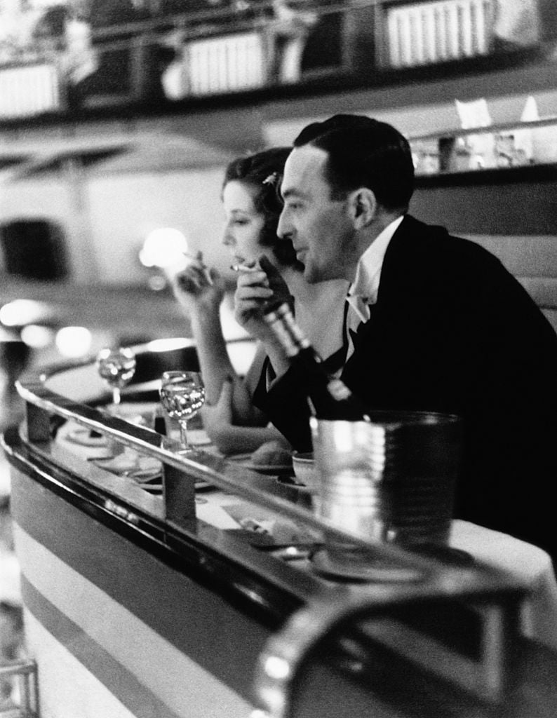 Dining Out by Hulton Archive/Getty Images, 1938. Diners at the former Prince Edward Theatre, now the London Casino, where they enjoy a full course meal and entertainment.. Open Edition Resin Photographic Print. Portrait orientation. Available at Electric Gallery, London, UK.