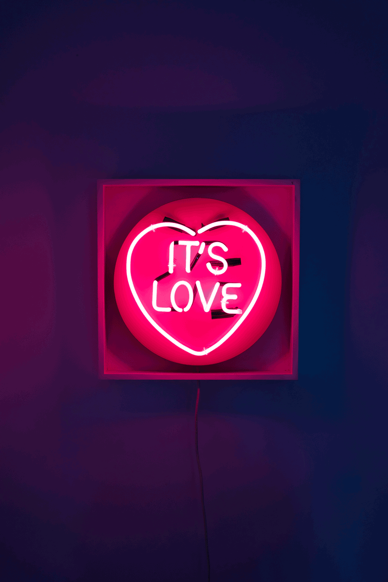 It's Love by Chris Bracey, a original love heart series with chris moon. cocktail pink neon set on wooden panel. box framed in white gallery wood. from 2012
